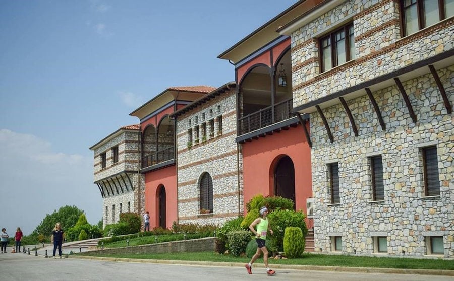 tourists running outside of the 'Oenogenesis Estate' stone building